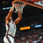 Professional basketball player performing an explosive dunk during an intense game, dynamic crowd in blurred stadium background, sweat and motion blur, professional lighting