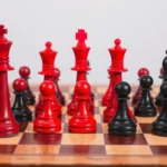 Professional checkers board with red and black pieces in mid-game position, wooden board with clear dark and light squares, dramatic lighting highlighting piece placement and strategic positioning